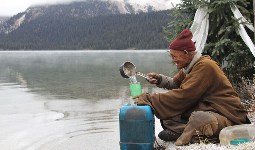 Tibetan old man get drinking water from the Cuopu Lake, Haizishan